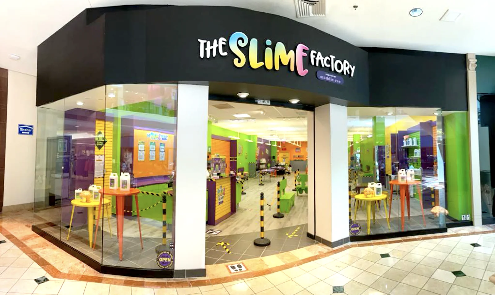 The Slime Factory storefront in Wellington, with an angled black rainbow-lettered sign, glass windows and colorful slime-lab walls inside.